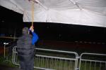 Un volontario mentre libera una copertura di una tenda dall'acqua piovana incessantemente caduta