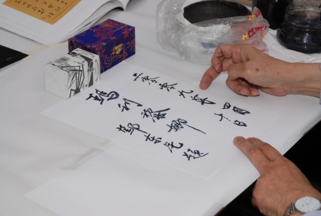 Il dott. Tang mentre realizza un cartoncino con ideogrammi in cinese antico