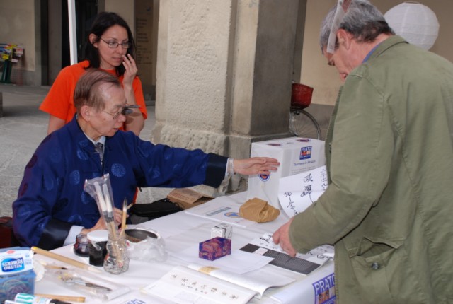 Il dott. Tang in Piazza del Comune a Prato mentre realizza ideogrammi in cinese antico per raccogliere fondi per la popolazione terremotata di Abruzzo