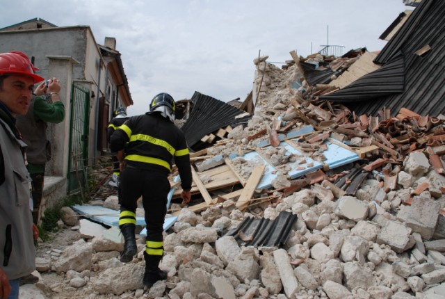Un vigile del fuoco mentre sale sopra un cululo di macerie nell'abitato di Castelnuovo