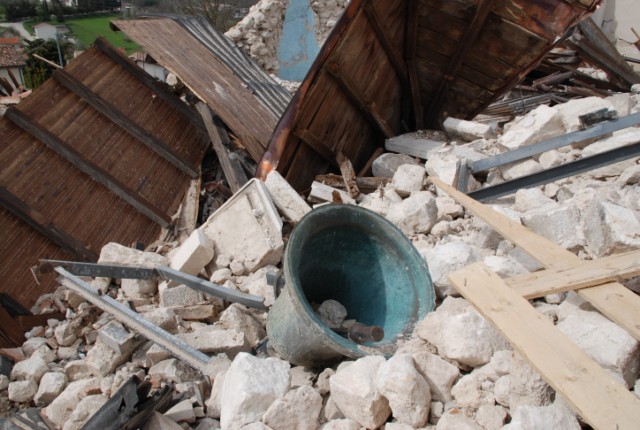 Una campana della chiesa di Castelnuovo adagiata sulle macerie della chiesa stessa