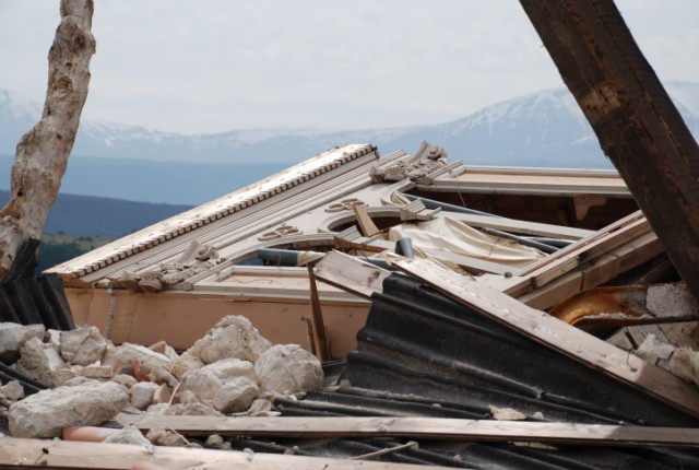 Una immagine della facciata di un edificio crollata ma non distrutta, adagiata in senso orizzonatale sulle macerie dell'edificio stesso