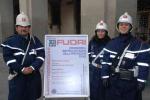 Tre agenti di Polizia Municipale di Prato accanto al manifesto dell'iniziativa fotografati in Piazza del Comune