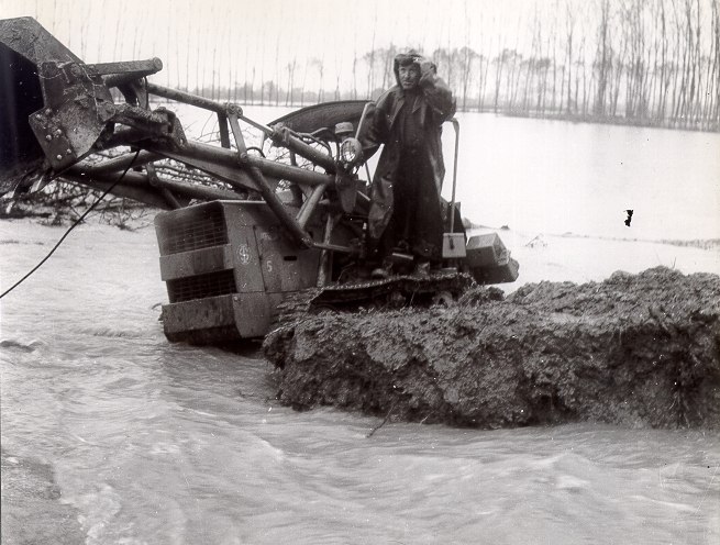 Una ruspa tenta di ripristinare un'argine distrutto dalla furia dell'acqua
