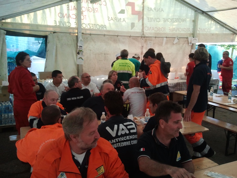 Volontari che mangiano all'interno della tenda adibita a mensa allestita dentro il campo